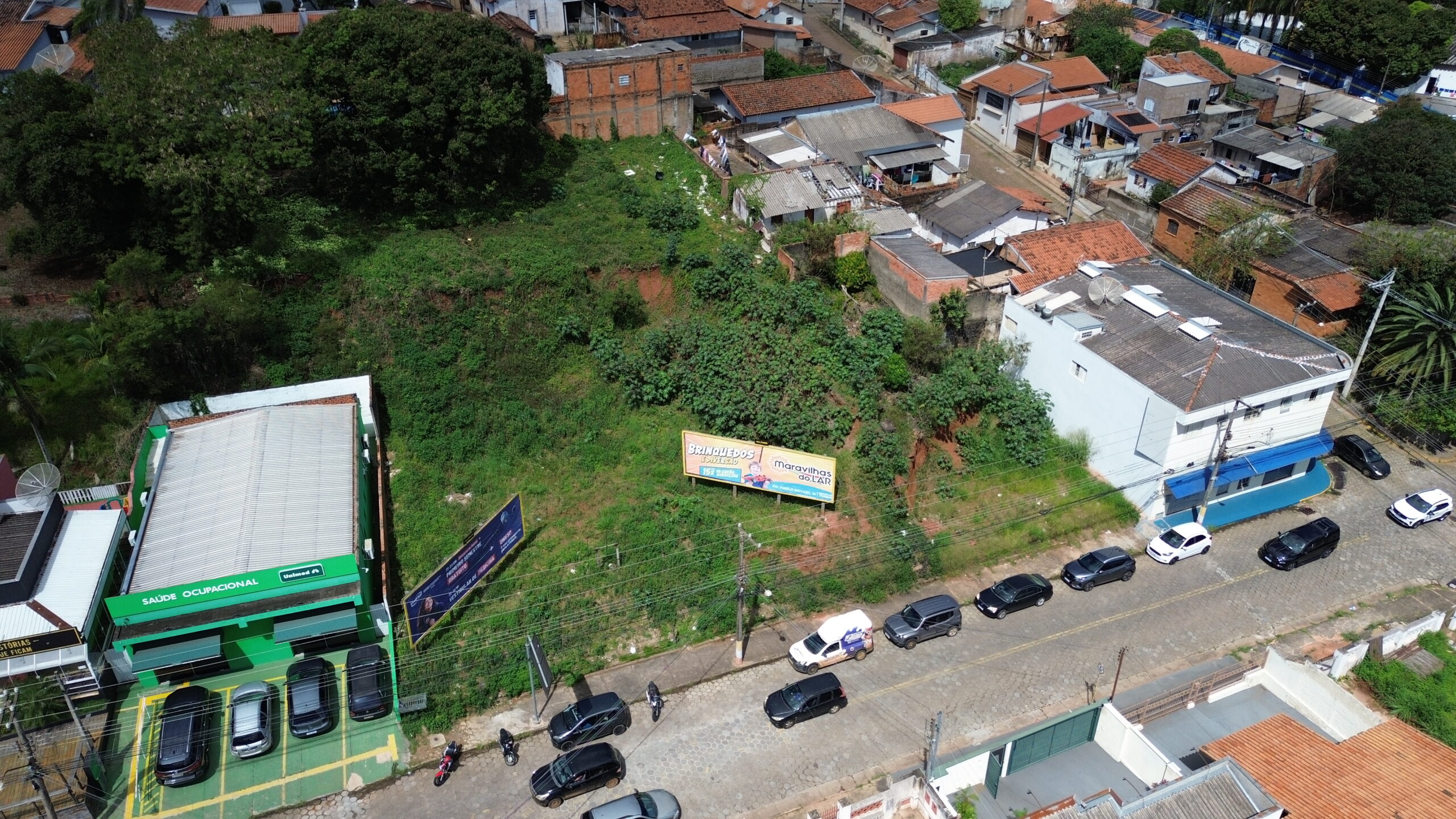 Vista de drone em diagonal da área, com a Unimed Saúde Ocupacional à esquerda e a rua de paralelepípedos à frente